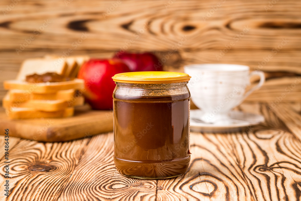  bottle of condensed milk on a wooden table with background of toasts and tea cup
