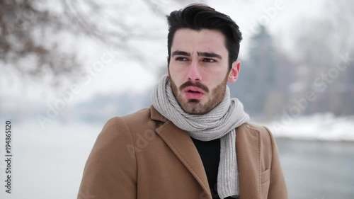 Handsome young man standing outside in winter, in snowy Turin, in Italy, on river docks
