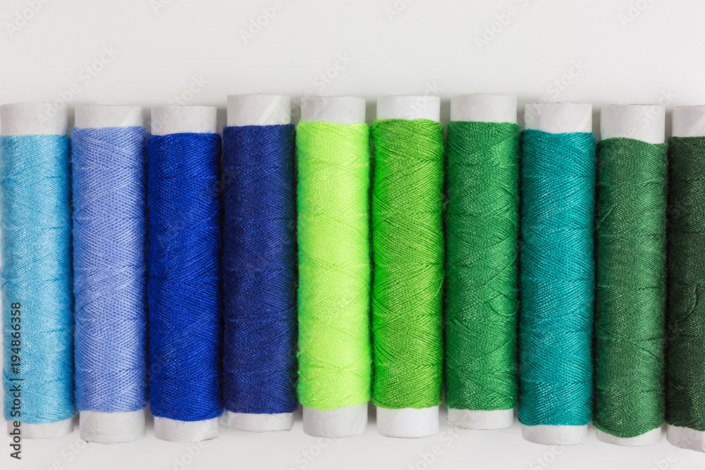 spools and bobbins of sewing thread in shades of blue and green spools and bobbins of sewing thread in shades of blue and green