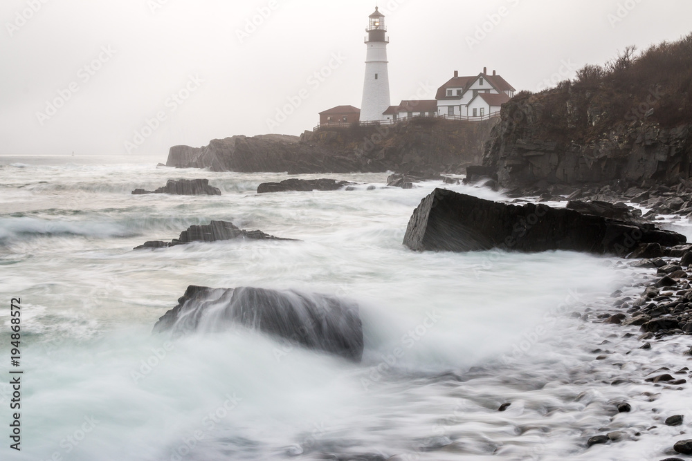 The tide rolling in during a foggy morning at Portland Head Lighthouse. 