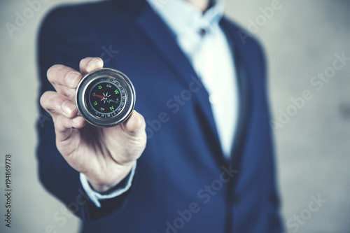Businessman holding compass showing direction concept for guidance