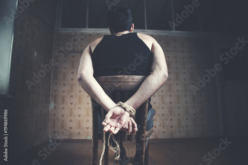 Photos young man tied to chair on dark background