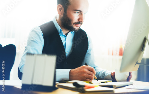 Bearded young businessman working on modern office. Consultant man thinking looking in monitor computer. Manager typing on keyboard in coworking workplace, startup project concept photo