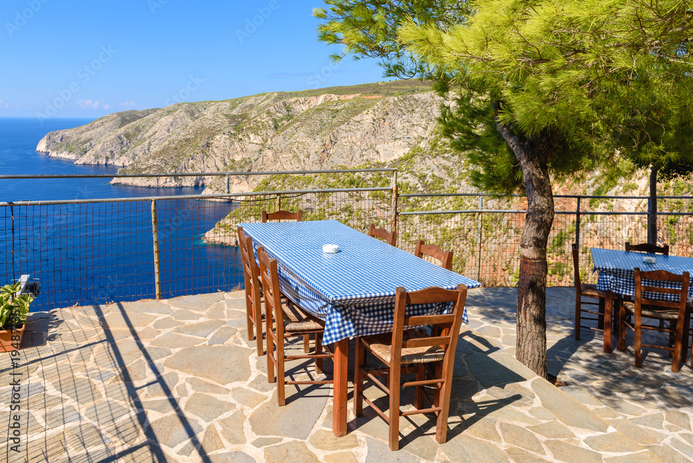 Tables with chairs on terrace of coastal restaurant in Porto Schiza on Zakynthos island. Greece.
