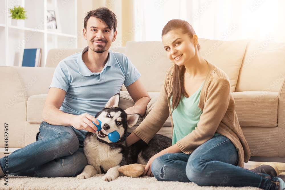 Young couple are playing with their puppy dog Husky Young couple are playing with their puppy dog Husky