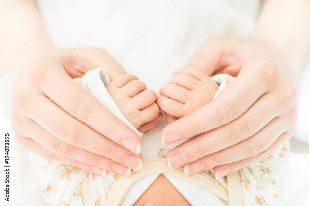Mother hand holding baby hands. Closeup no retouch, bright pastel colors.