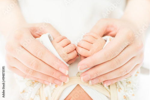 Mother hand holding baby hands. Closeup no retouch  bright pastel colors.