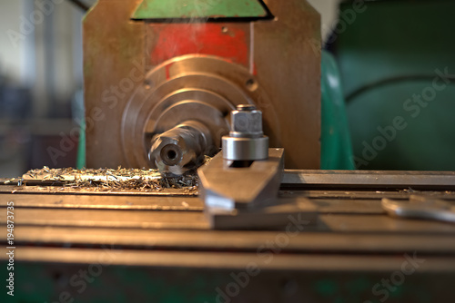 The detail is clamped by clips on a table. Dry boring by a trailer mill with a smoke and steam. The look with a side, the worker operates manufacturing process at plant.