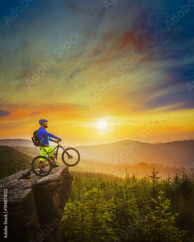 Fototapeta Naklejka Na Ścianę i Meble -  Mountain biker riding at sunset on bike in summer mountains forest landscape. Man cycling MTB flow trail track. Outdoor sport activity.