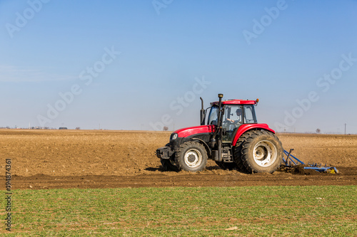 Farmer in tractor preparing land with seedbed cultivator as part of pre seeding activities in early spring season of agricultural works at farmlands.