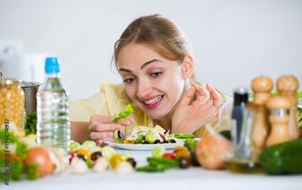 Happy young woman with plate of vegetable salad