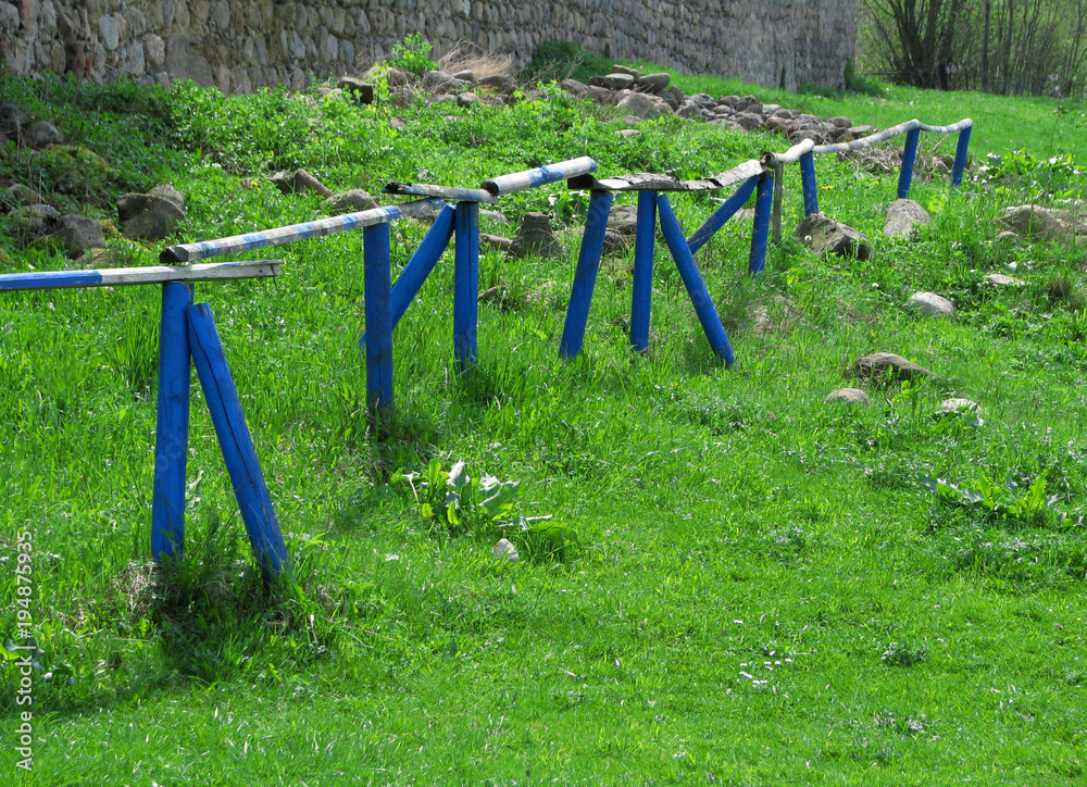 Bright blue rural wooden village fence landscape at wonderfull fresh green grass summer background Bright blue rural wooden village fence landscape at wonderfull fresh green grass summer background