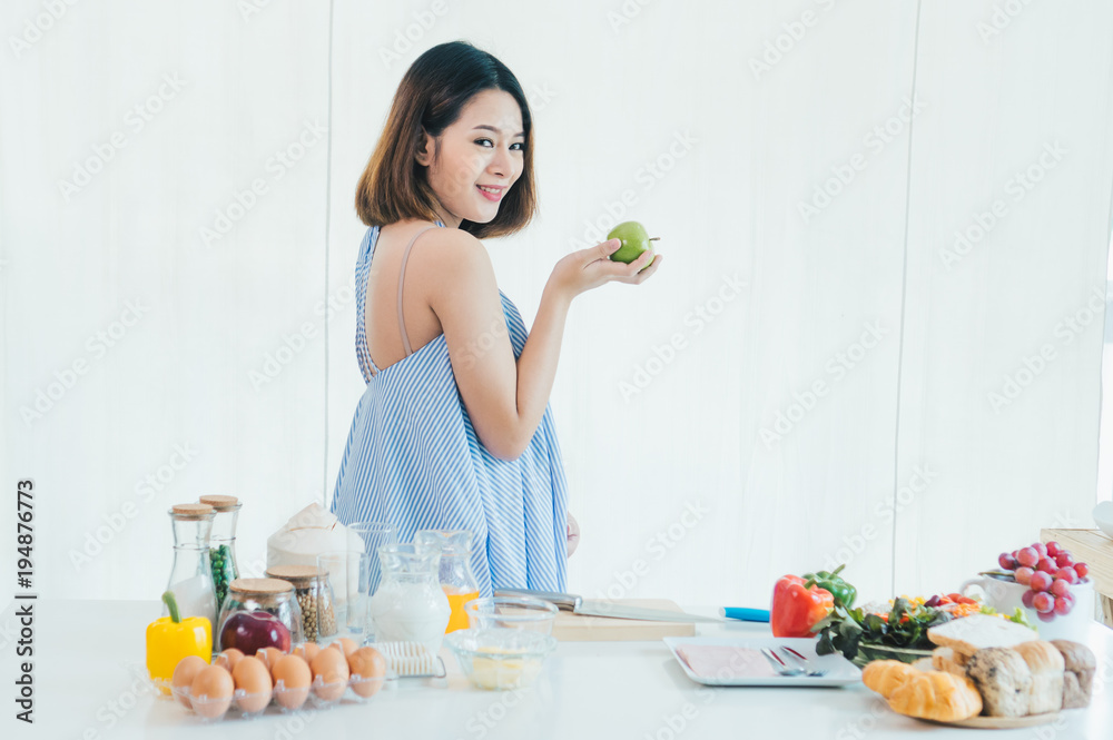 A pregnant Asia beautiful girl holds the green apple A pregnant Asia beautiful girl holds the green apple
