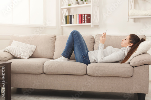 Young girl using mobile phone on sofa