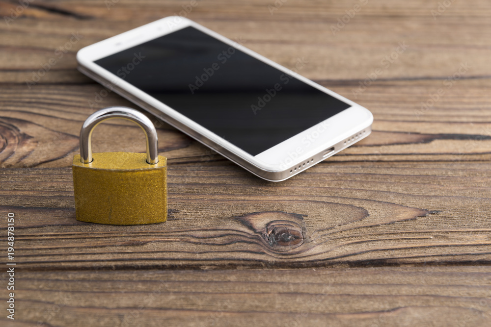 lock, smartphone on a wooden background. graphic key, protection against hacking. lock, smartphone on a wooden background. graphic key, protection against hacking.