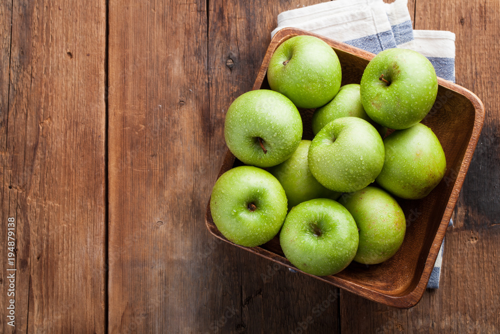 Ripe green apples in a wooden bowl on an old rustic table. Useful fruits on wooden background. Top view with copy space Ripe green apples in a wooden bowl on an old rustic table. Useful fruits on wooden background. Top view with copy space