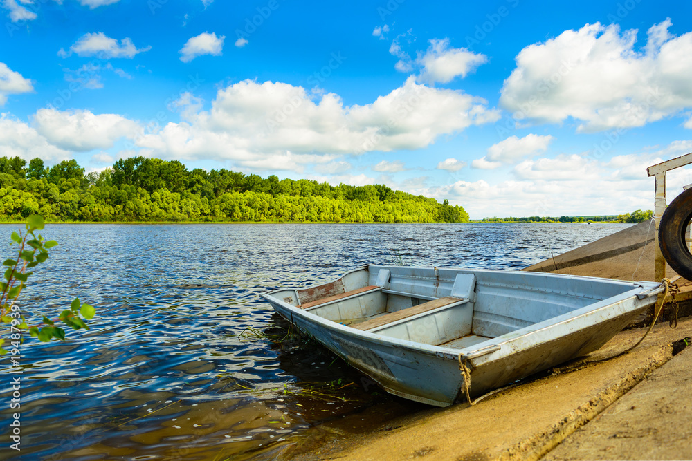 Minimalistic horizontal landscape with a boat on a calm river, green forest and cloudy sky. It's perfect.