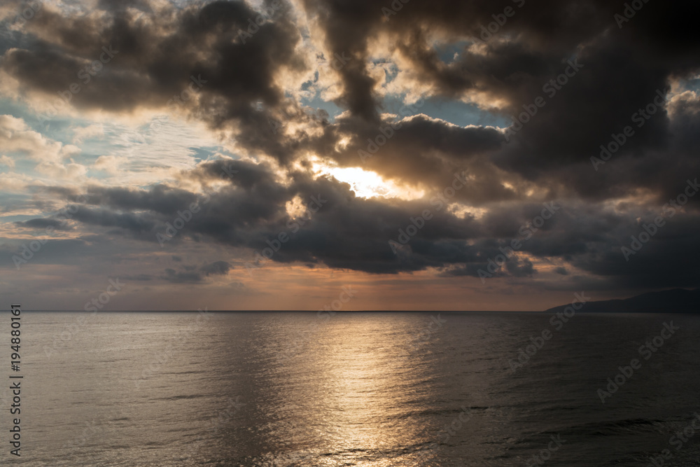 The picturesque sunrise over the Mediterranean sea. Cloudy weather, dark clouds cover the rising sun