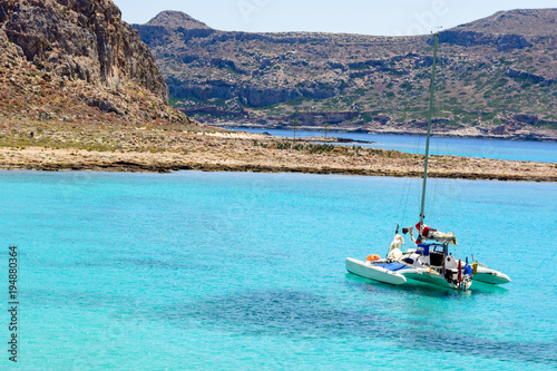 white sailing catamaran is anchored in the azure Harbor in the windless, without people