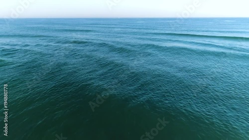 Drone shot of sea tracking backwards and revealing the shore