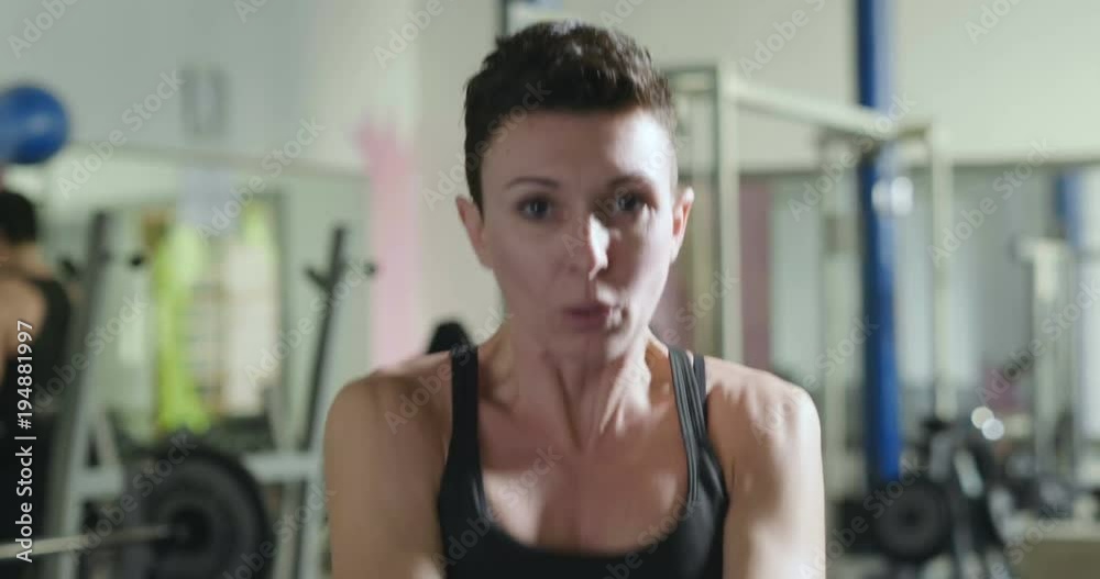 A woman trains himself in the gym performing both free-body exercises, such as push-ups and abdominals, and exercises with rocker arms and professional equipment. Concept of: sport, power, muscles.