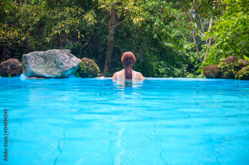 Woman in blue water. Loose hair girl in open swimming pool. Tropical jungle resort. © Elya.Q