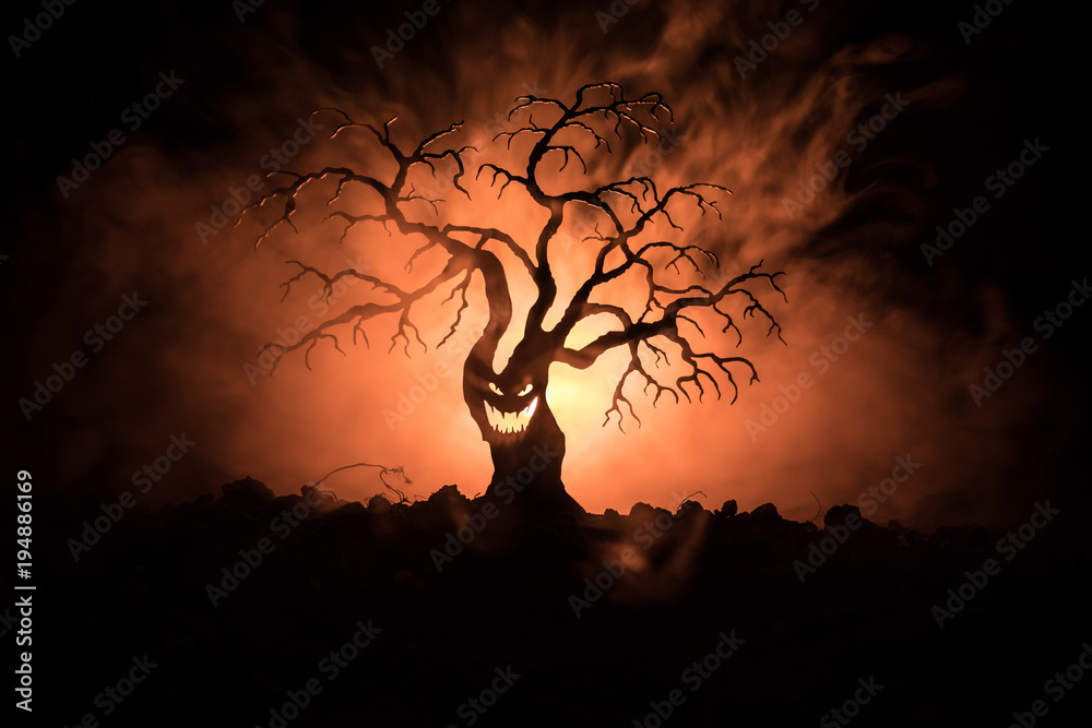 Silhouette of scary Halloween tree with horror face on dark foggy toned  background with moon on back side. Scary horror tree with zombie and demon  faces. Stock Photo | Adobe Stock