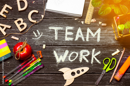 The inscription work in a team on the background of a school board, a table of wooden dark boards. Top view. The concept of education, cooperation and collective. Creative mess, teamwork.