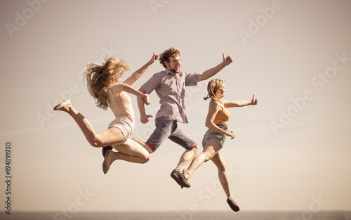Carefree friends jumping by sea ocean.