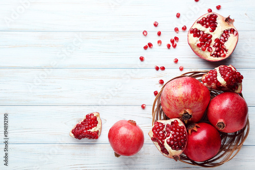 Ripe and juicy pomegranate in basket on wooden table