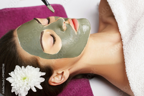 Woman with clay facial mask in beauty spa. Skincare. Beauty Co