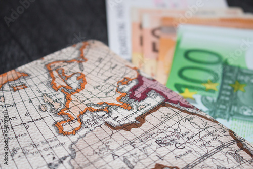 Money, Airplane ticket and map. Eurobanknotes with boarding pass and map, on black wooden background. Business and travel planning concept..