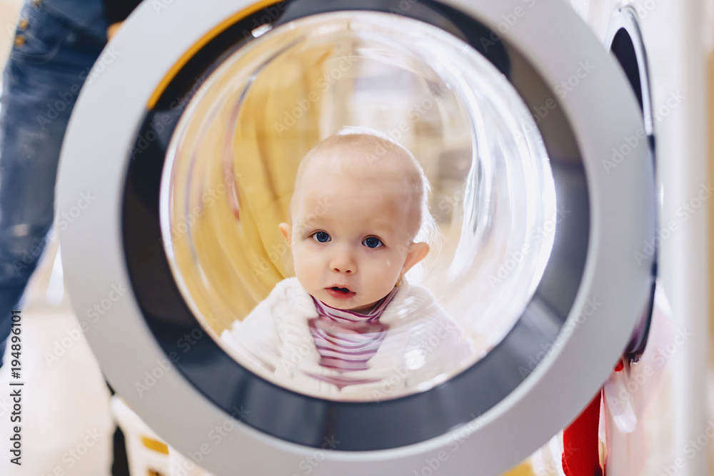 The baby looks through the window of the washing machine The baby looks through the window of the washing machine