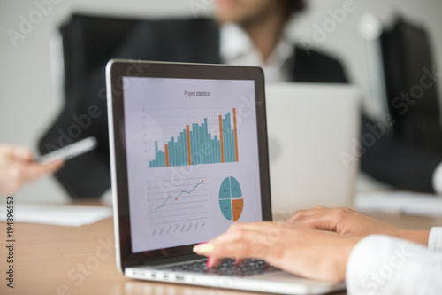 Businesswoman working with statistical report at team meeting analyzing marketing result graphs charts online on laptop screen, business software for project data analysis concept, close up view