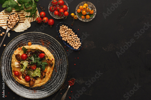 Hummus with vegetables and seafood on black background
