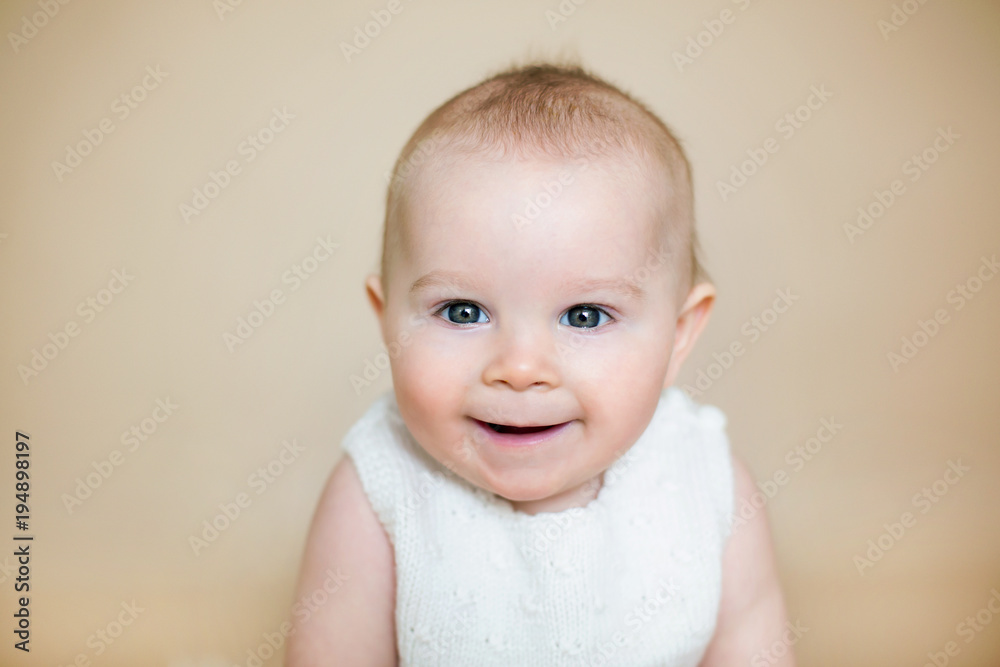 Close portrait of cute little baby boy, isolated on beige background, baby making different facial expressions, smiling, laughing
