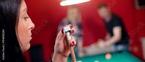 Brunette is chalking pool cue
