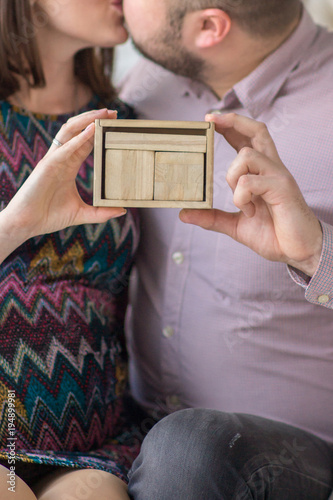 wooden calendar without numbers in the hands of a pregnant girl and her partner