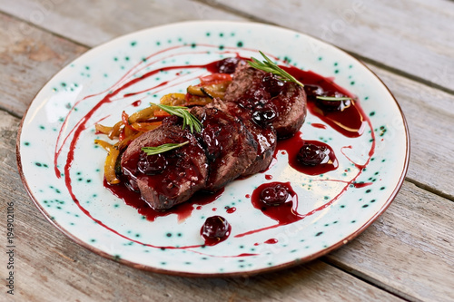 Appetizing beef meat with sweet cherry sauce. Meat in sweet red sauce on plate. Delicious european restaurant food.