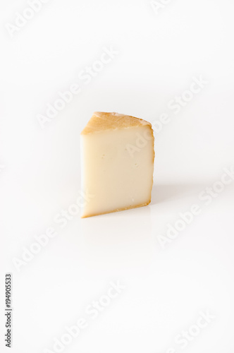 Slice of Italian or French hard cheese on white backgrund