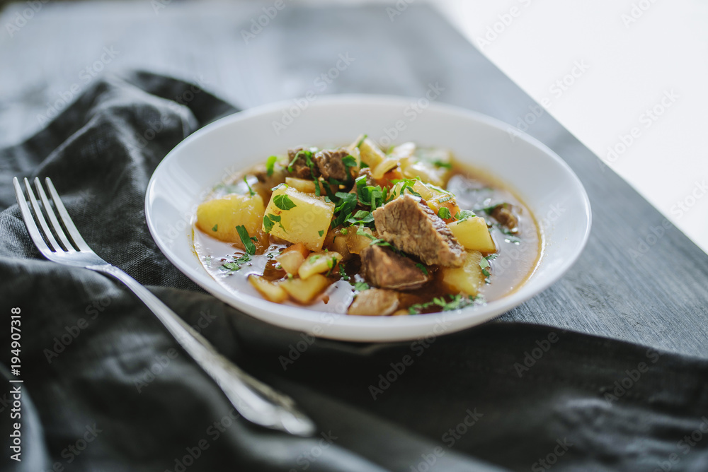 Irish beef stew with fresh parsley on a dark wooden background in natural light Irish beef stew with fresh parsley on a dark wooden background in natural light