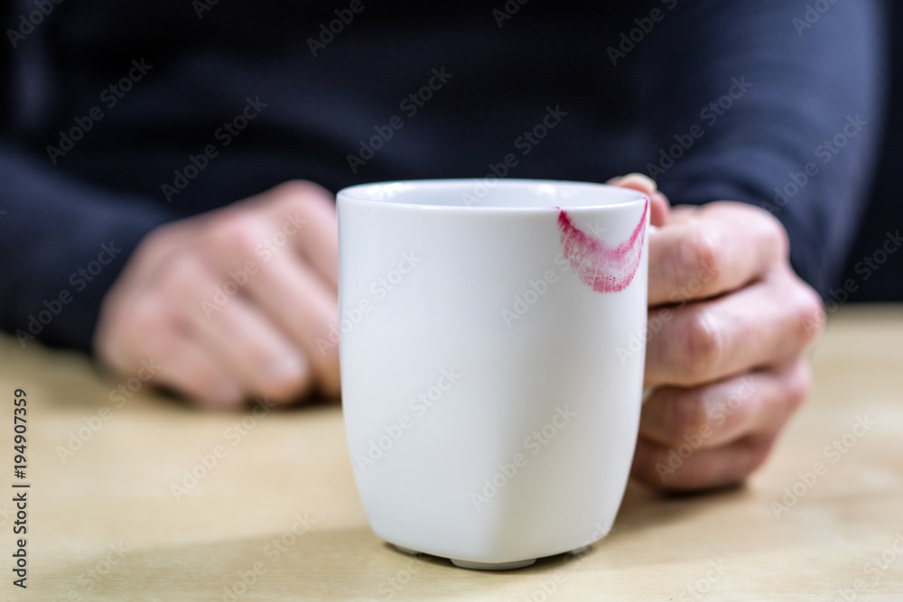Empty white mug with gloves. Hands in warm gloves holding a china mug on a wooden kitchen table. Empty white mug with gloves. Hands in warm gloves holding a china mug on a wooden kitchen table.