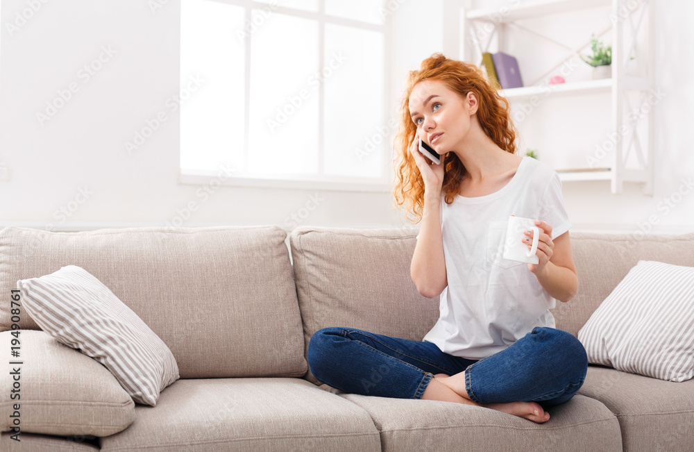 Attractive ginger girl making a call on phone at home Attractive ginger girl making a call on phone at home