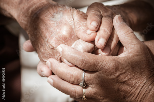 Fényképezés Hands of Asian woman holding elderly grandfather man hands wrinkled skin with feeling take care of Love