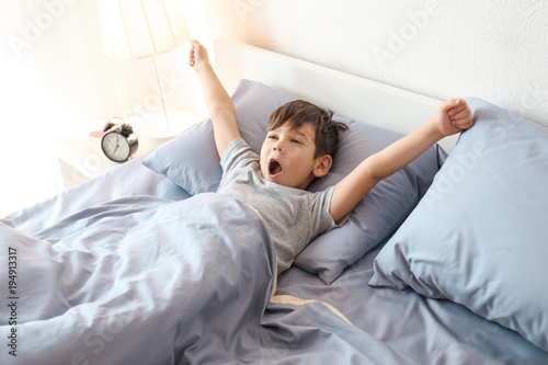 Cuadro en lienzo Cute little boy stretching in bed at home