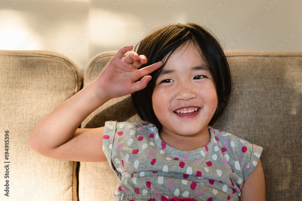 Young girl sitting on couch smiling moving bangs out of face Young girl sitting on couch smiling moving bangs out of face