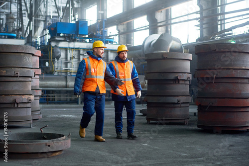 Fotografie Team of hard-working technicians wearing hardhats and reflective vests walking a