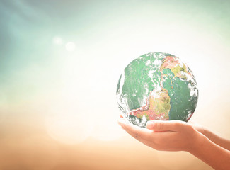 Human hands holding earth globe planet over abstract blurred background with sunlight