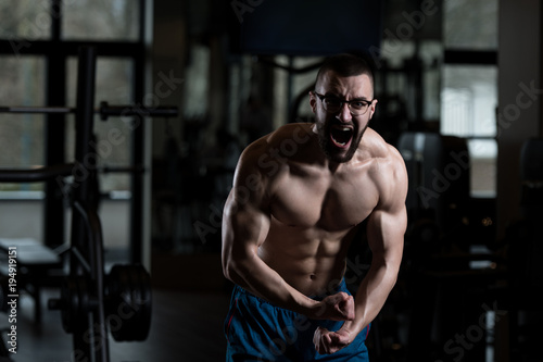 Muscular Geek Man Flexing Muscles In Gym