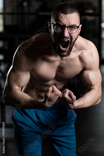 Young Bodybuilder Wearing Eyeglasses Flexing Muscles